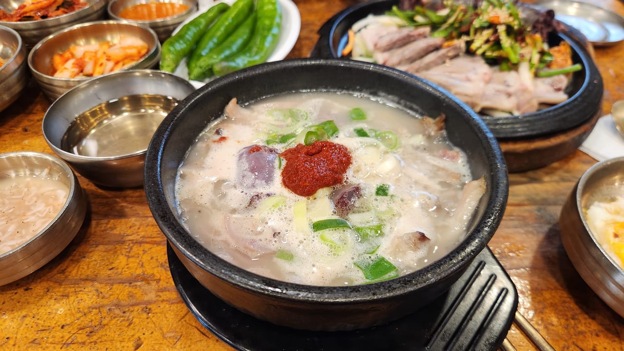 Pale sundae gukbap broth with red chilli seasoning before mixing