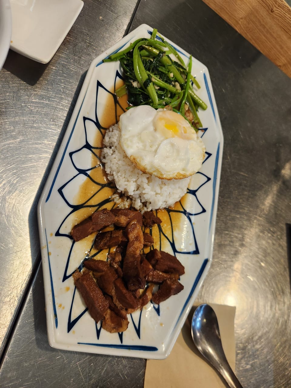 Vietnamese rice plate with soy-braised pork, morning glory and a fried egg