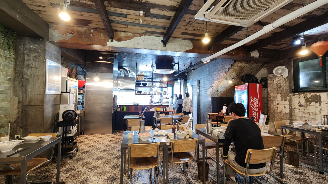 Interior of Phopular with exposed brick, patterned tile floor and wooden chairs
