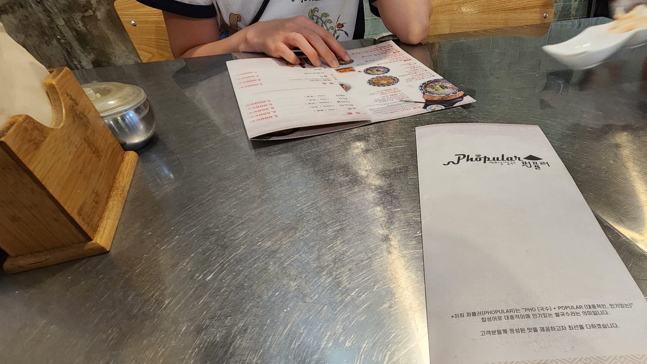 Brushed steel table with the folded Phopular menu at a Vietnamese restaurant in Seoul